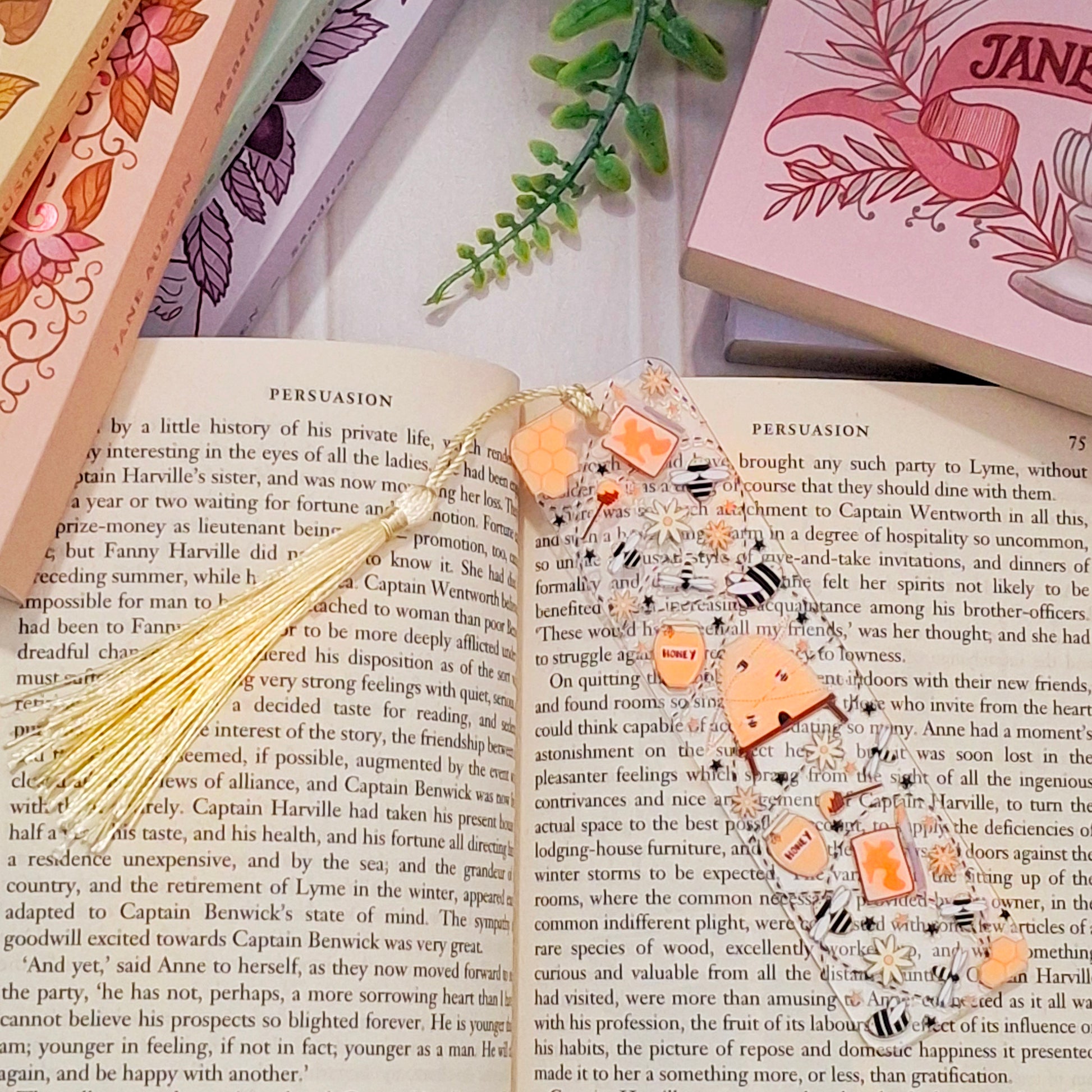 Bee, bee hive and honeycomb bookmark with tassel for nature lovers, lying across an open book page.