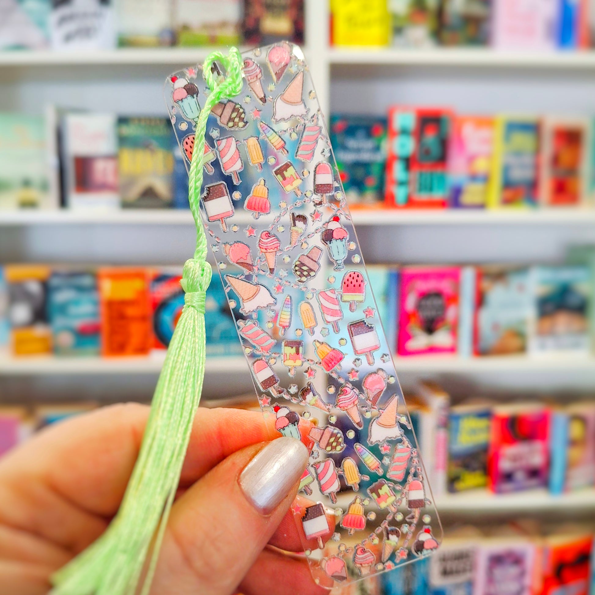 Ice cream themed acrylic bookmark with tassel, held in front of a bookshelf.