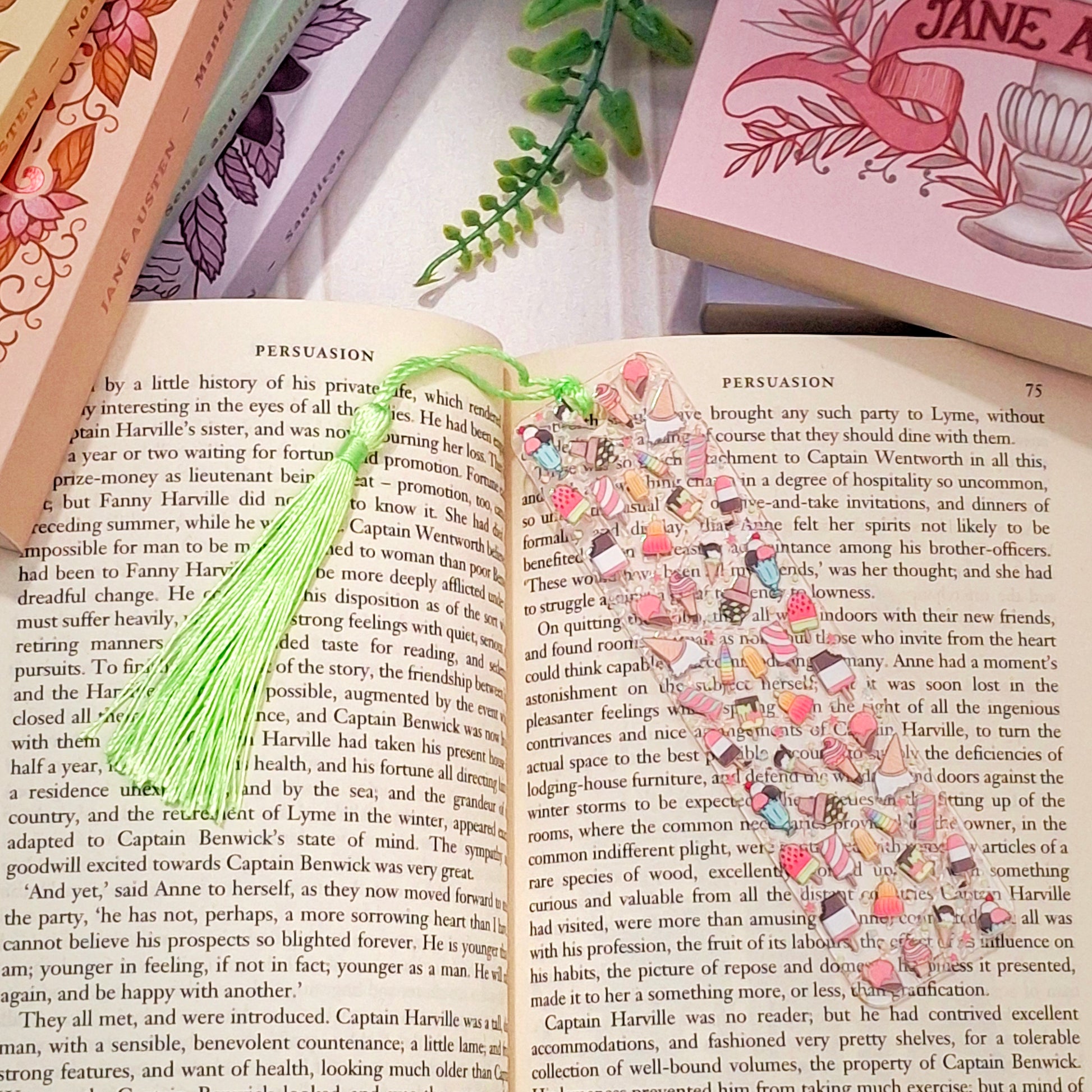 Acrylic bookmark with tassel featuring an ice cream design, lying on an open book.