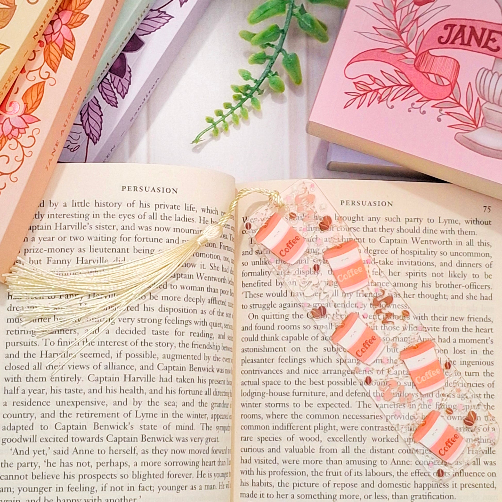Cosy morning coffee bookmark with tassel for readers, lying across an open book page.