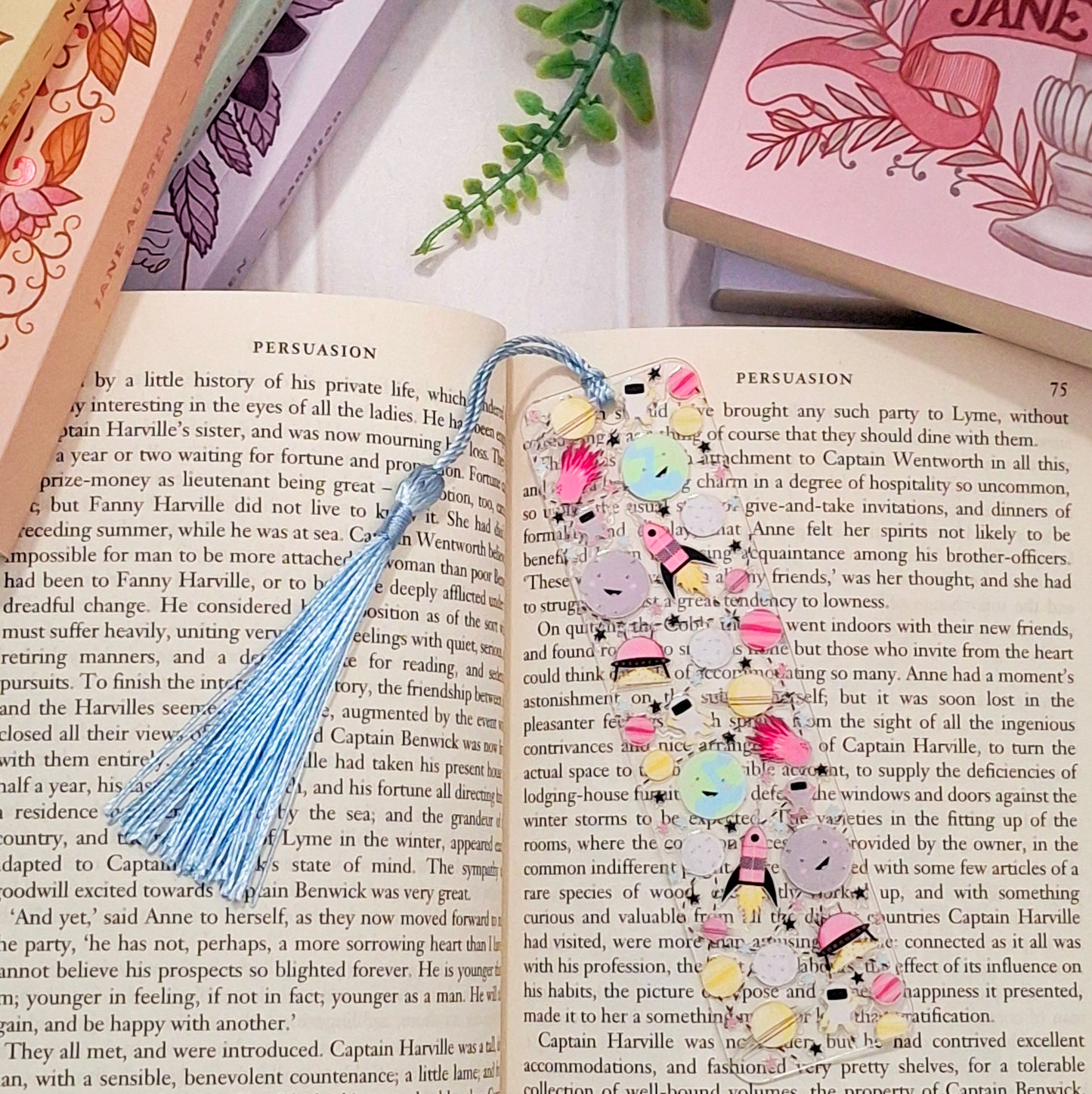 Space themed bookmark with tassel, lying on an open book.