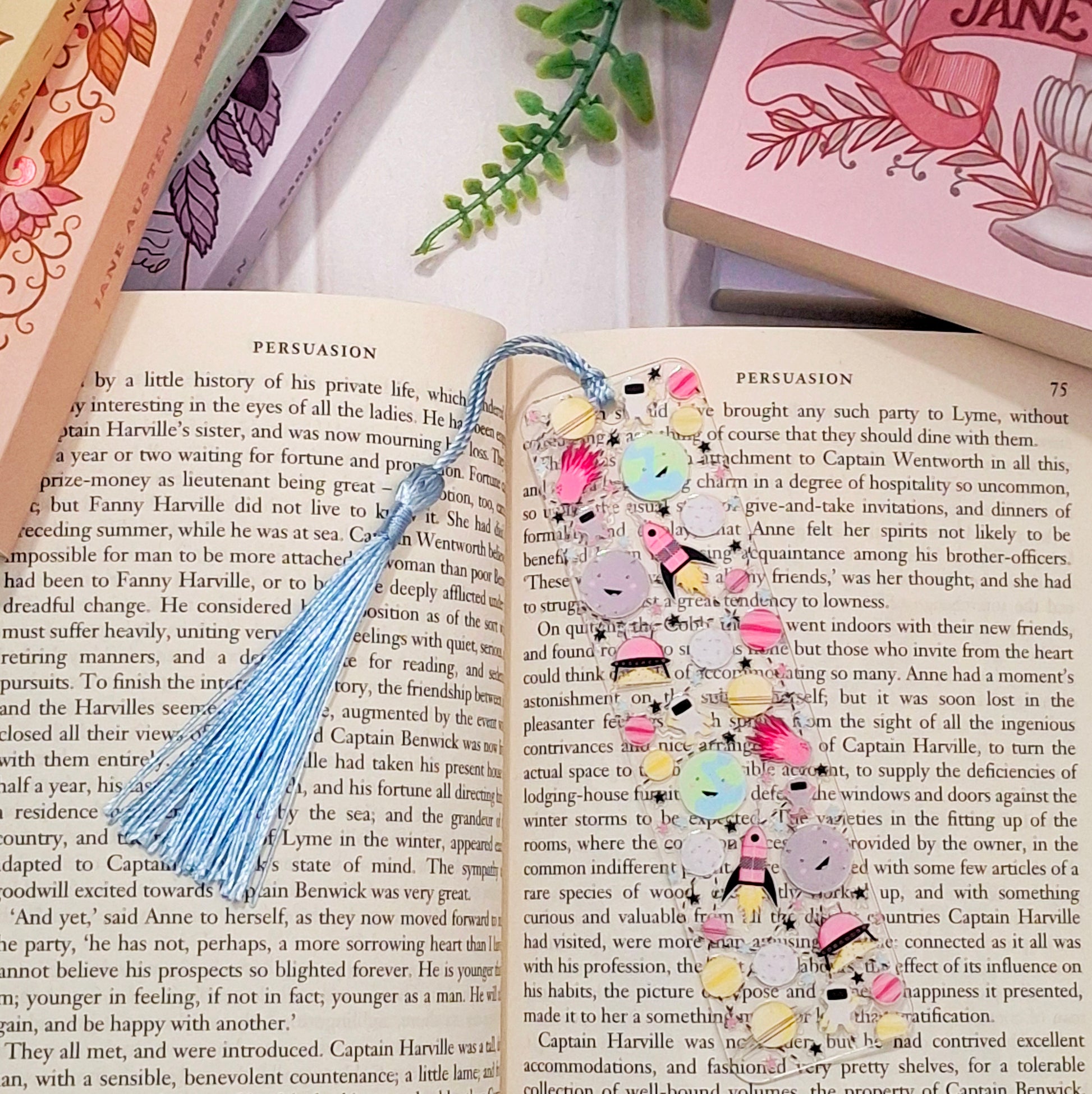 Space themed bookmark with tassel, lying on an open book.