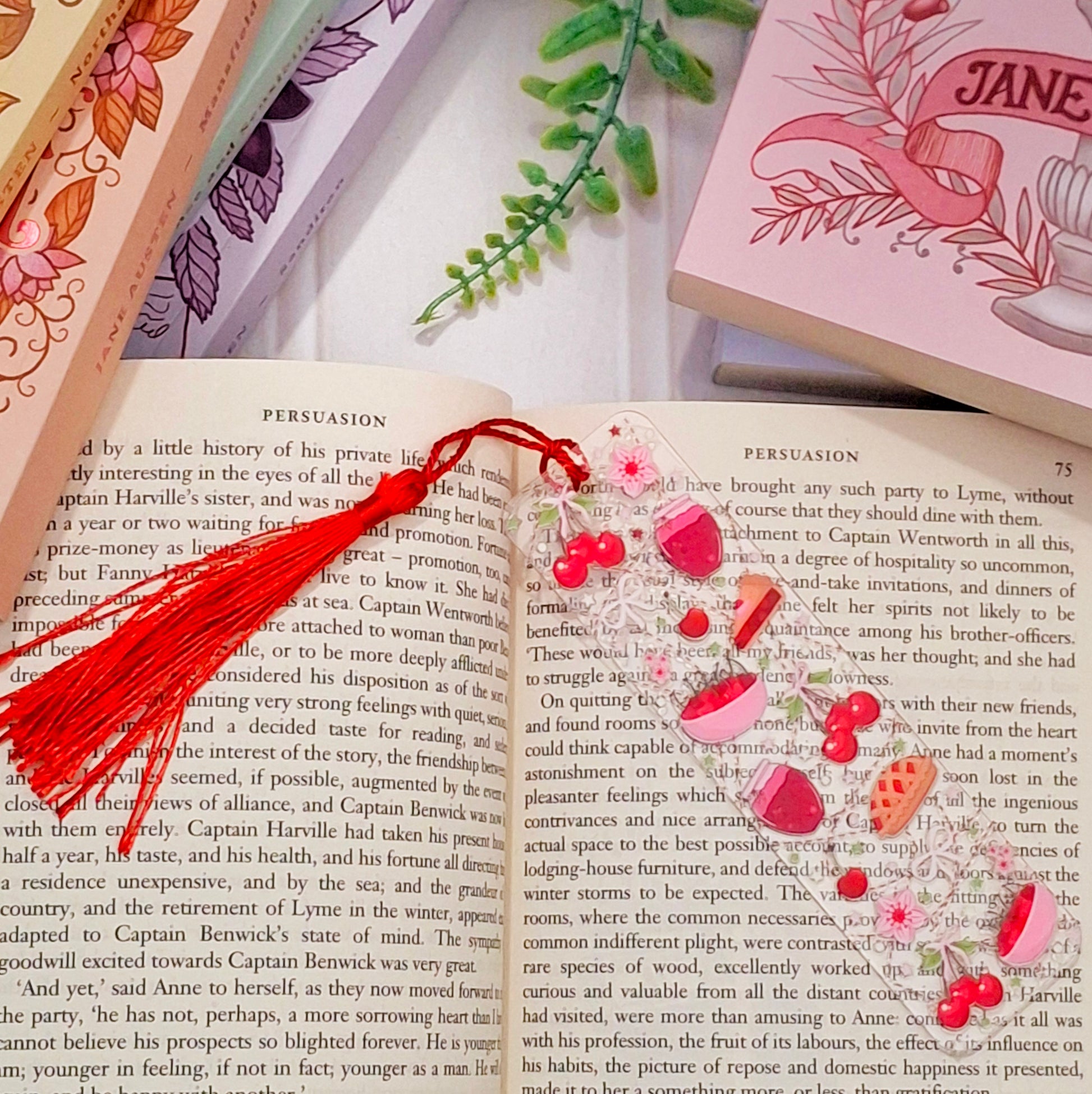 Cute cherry pie themed bookmark with tassel for book lovers and bakers, lying across an open book page.
