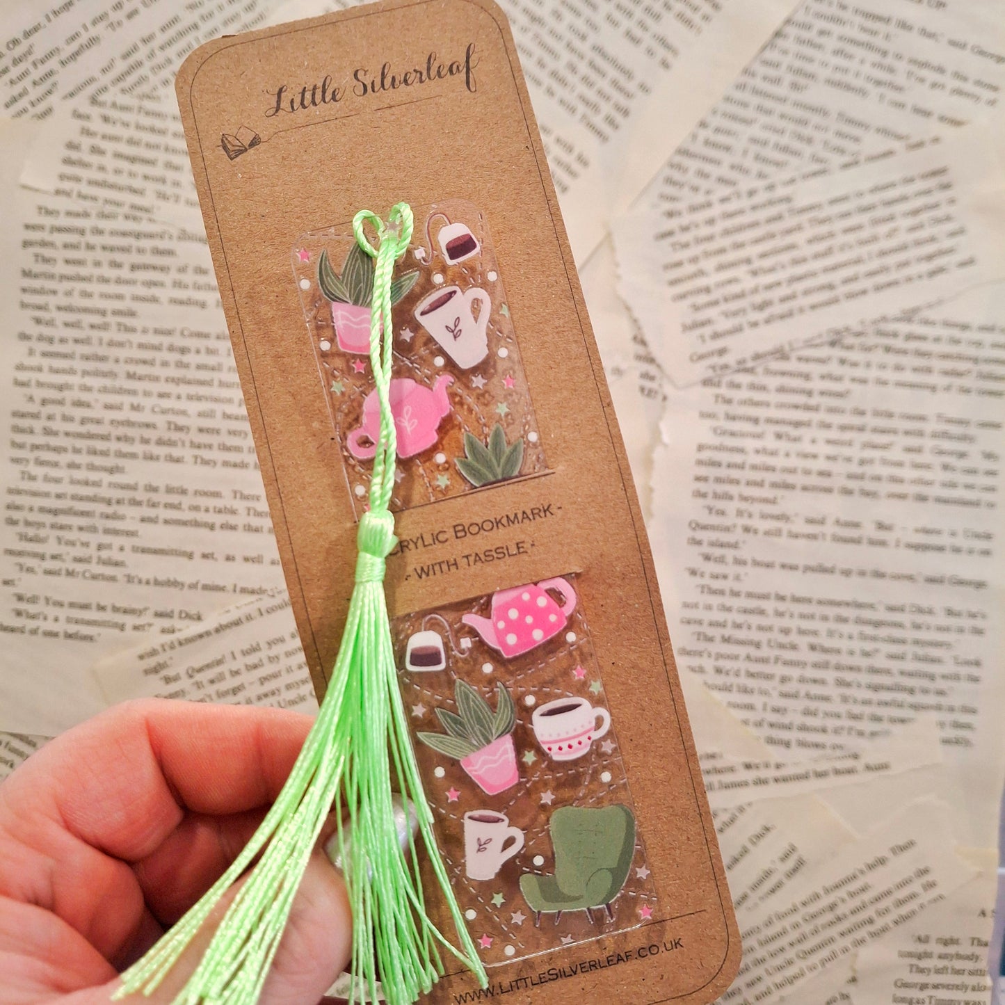 Cosy tea themed bookmark with botanical details and a tassel resting on book pages.
