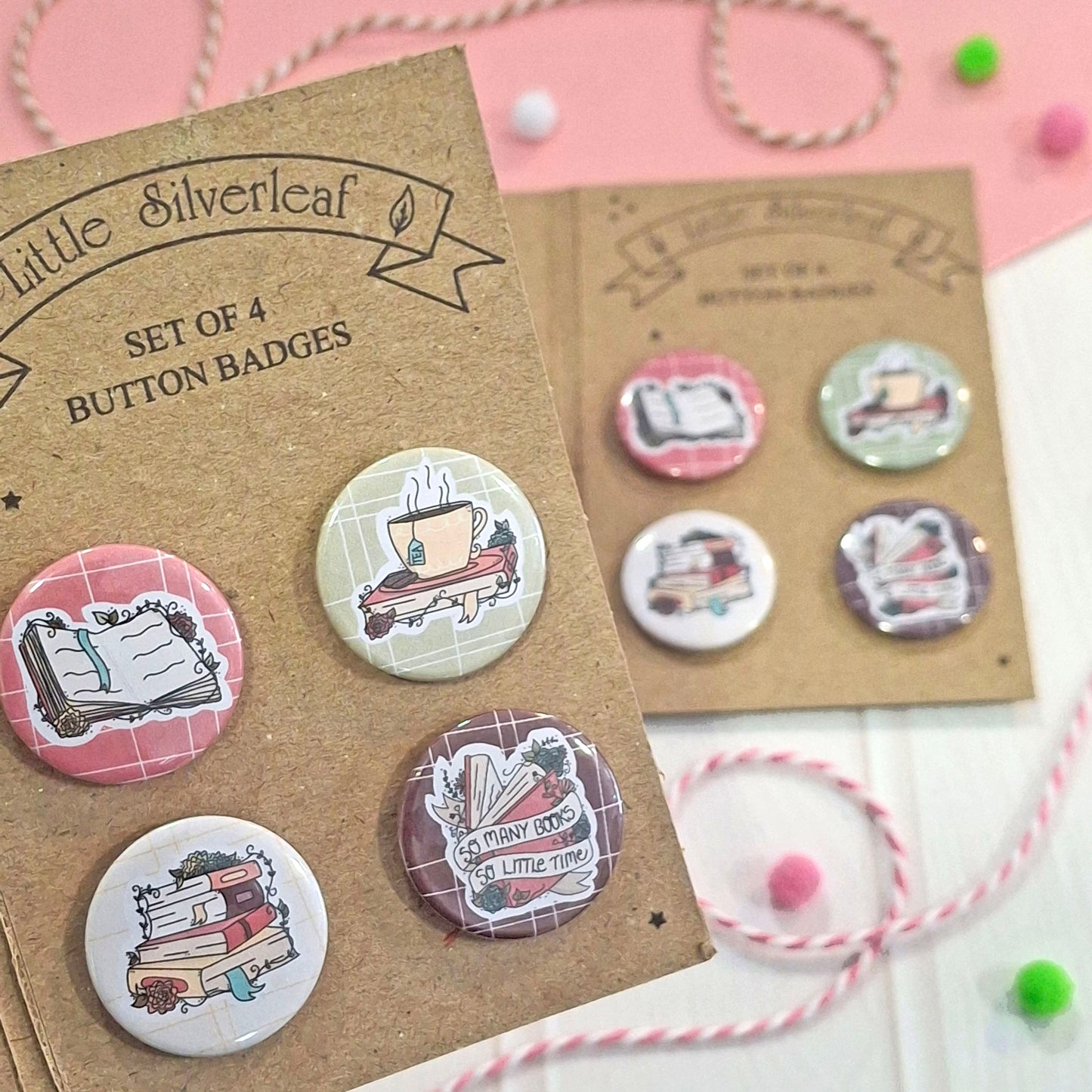A set of four round button badges displayed on brown kraft cardstock, with the text 'Little Silverleaf' and 'SET OF 4 BUTTON BADGES.' The badges feature illustrated book-themed designs, including an open book, a tea cup, stacked books, and a book with a ribbon.