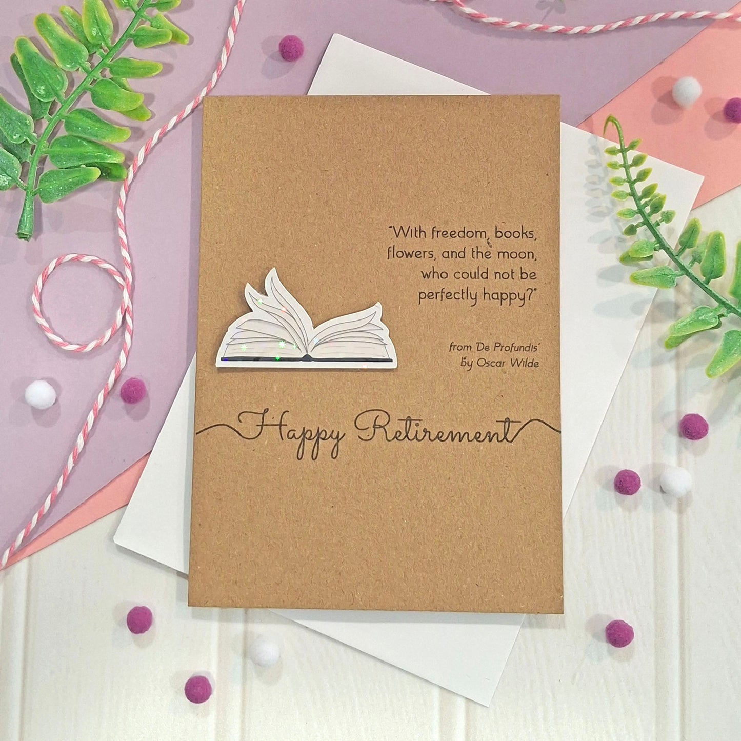 A handmade retirement card made from brown kraft card with illustrated book pages in a raised, holographic embellishment, a quote by Oscar Wilde, and the words 'Happy Retirement' in elegant script. 