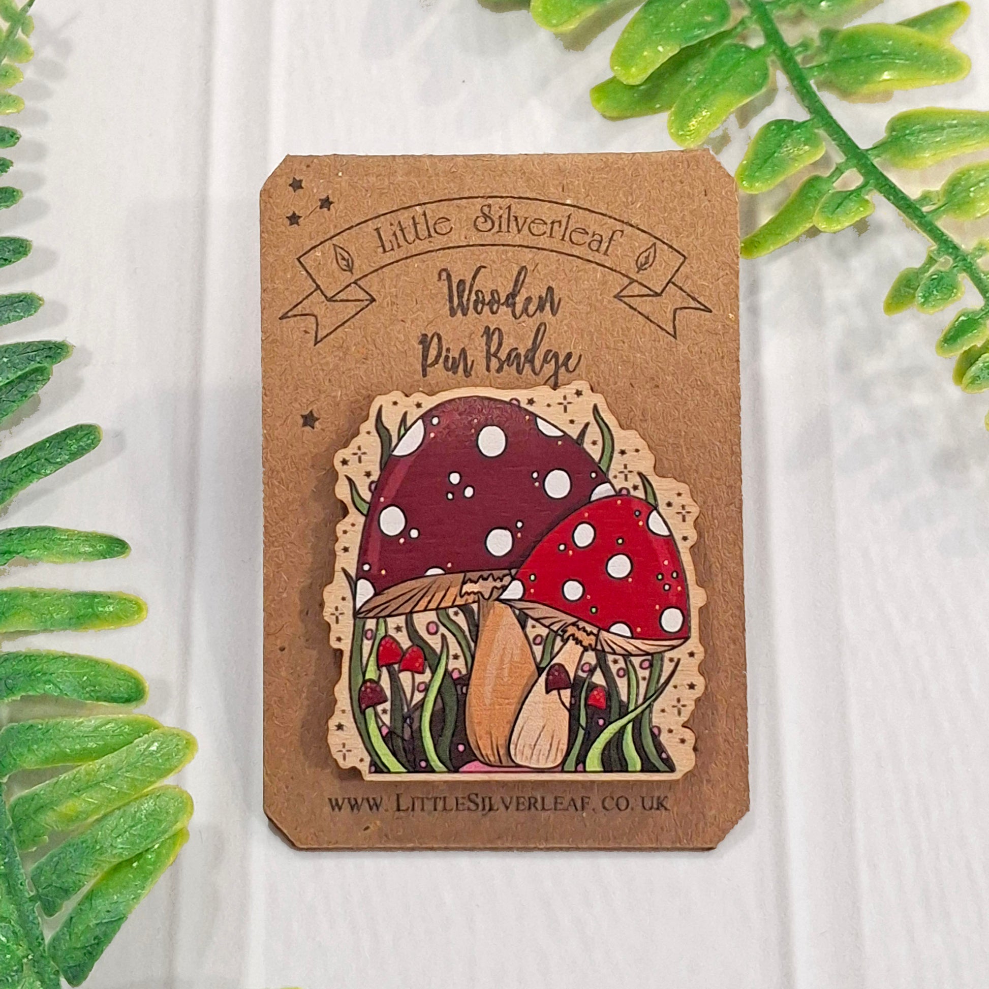 A wooden pin badge featuring a hand-drawn magical mushroom illustration, mounted on a brown kraft card. The card reads 'Little Silverleaf Wooden Pin Badge'.