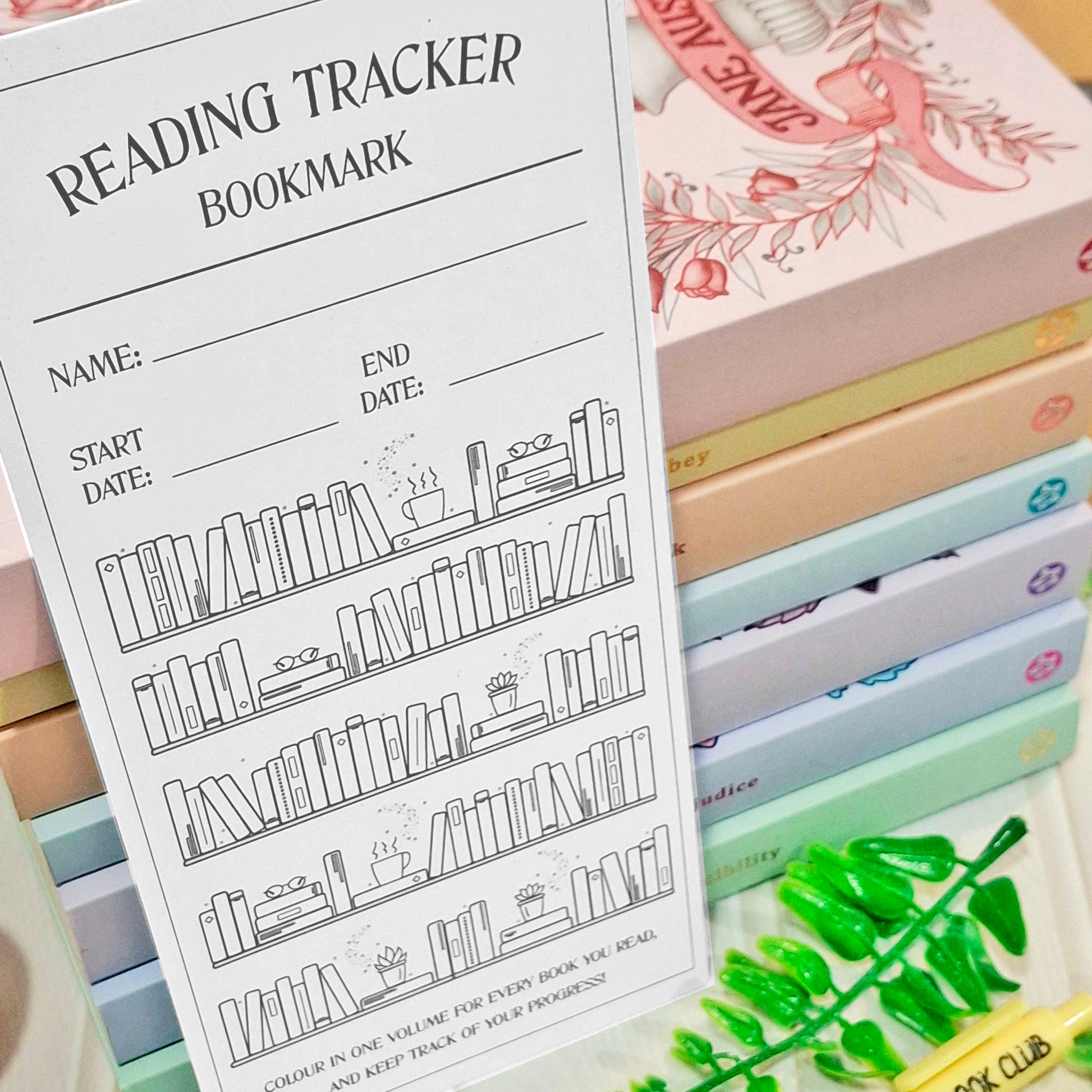 A white reading tracker bookmark with black line art of bookshelves and fill-in lines for name, start date, and end date, displayed in front of a stack of pastel-colored books.